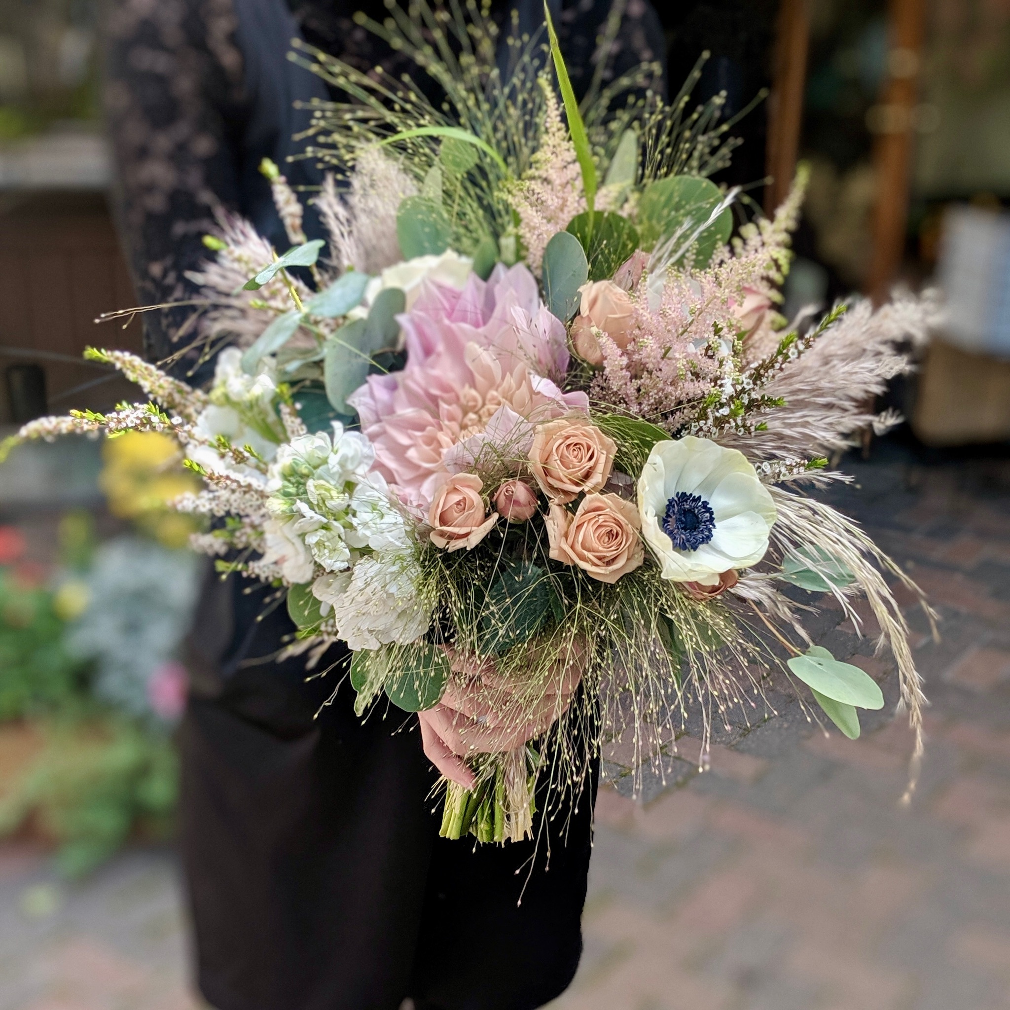 Bride holding a blush and neutral garden-style bridal bouquet with roses, anemone, grasses, and eucalyptus designed by A Secret Garden Vail Colorado