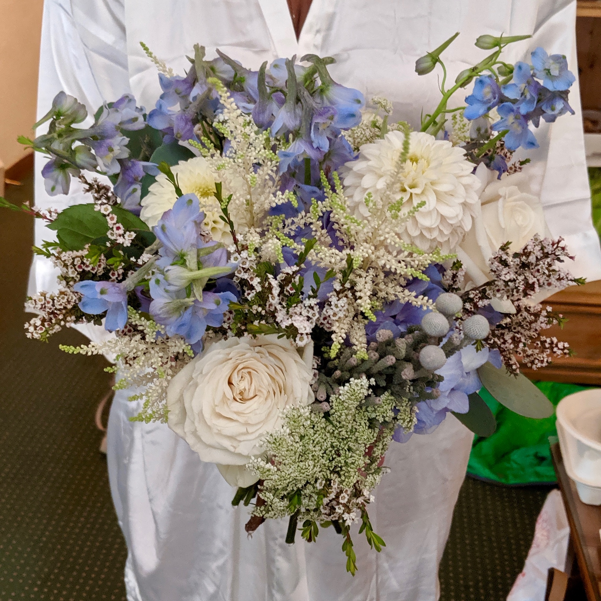 Bride holding a blue and white garden-style bridal bouquet with delphinium, ranunculus, and seasonal blooms designed by A Secret Garden Vail Colorado